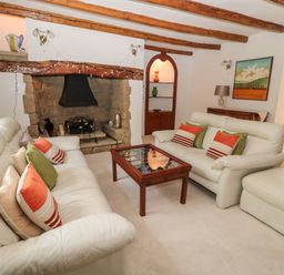 A living room with two white sofas a wooden coffee table and a stone fireplace at 1A Chantry Place in Morpeth