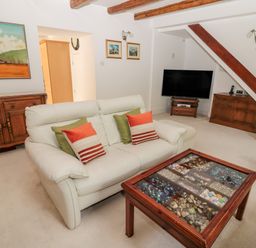 A sitting room with a white sofa and a glass top coffee table displaying stones and shells at 1A Chantry Place in Morpeth