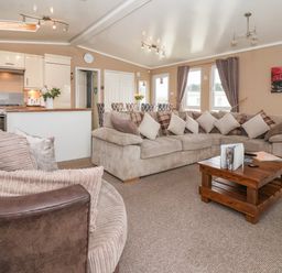 A living room with sofas cushions and a wooden coffee table next to an open kitchen and dining area at Jonstone Pines in Cayton Bay near Scarborough