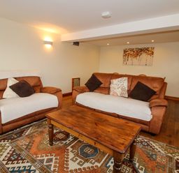 A living room with two brown sofas a wooden coffee table and a patterned rug at Norton Cottage in Craven Arms