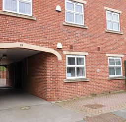 A red brick building with multiple white windows a gated archway and a green fence at Cadliam Whitby