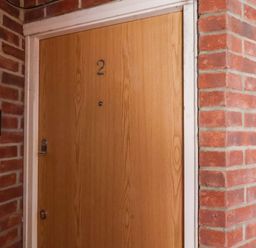 A wooden door with the number 2 on it surrounded by red brick walls