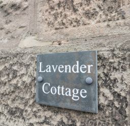 A sign reading Lavender Cottage mounted on a stone wall at Lavender Cottage in Glanton