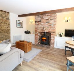 A living room with a wood burning stove and brick fireplace at Captain's Cottage in Sheringham