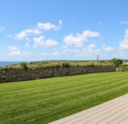 A green lawn with a stone wall and ocean view at Atlantic View in Germoe