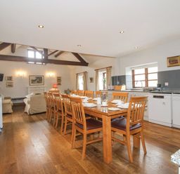 A kitchen and dining area with a long wooden table and chairs and a seating area at The Onibury in Craven Arms