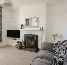 A living room with a fireplace television gray sofa and floral curtains at Monfa in Cemaes Bay
