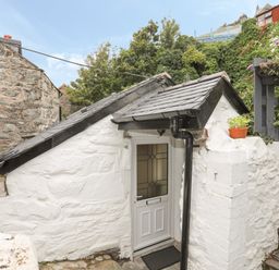A white stone building with a small roof and a door at Glan Meon Cottage in Barmouth