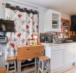 A kitchen with a table and stools at Tiny Willow in Farrington near Child Okeford