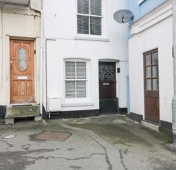 A small courtyard with three doors and two windows on the surrounding buildings at Bay Tree Cottage in West Looe