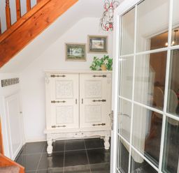 Hallway with a wooden staircase white cabinet on black tiled floor at The Old Mill in Neyland near Milford Haven