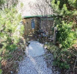 A pathway with stone steps and gravel surrounded by trees leading to a small wooden building at The River Lodge in Oban