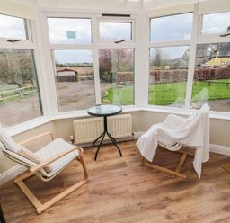 A sunroom with two wooden chairs and a small round glass table between them at The Shieling in Warkworth