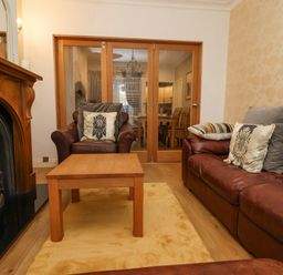 A living room with leather sofas a wooden coffee table a fireplace and glass doors leading to a dining room at 202 Salisbury Terrace in York