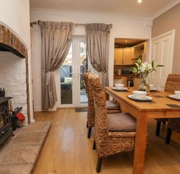 A dining area with wicker chairs around a wooden table and a wood stove next to double glass doors at 202 Salisbury Terrace in York