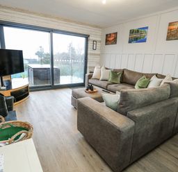 A living room with a sofa and a television at Daisy Cottage in Benllech