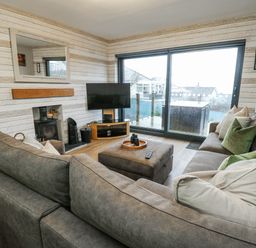 A living room with a sofa, television, and fireplace at Daisy Cottage in Benllech