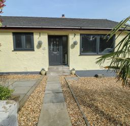 A front entrance with a pathway and garden at Daisy Cottage in Benllech