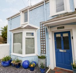 The front entrance of a blue house with a blue door and potted plants at Arwel in Nefyn