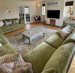 A living room with green sofas and a coffee table at Trevose House in Crantock