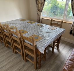 A dining table with wooden chairs and tablecloth at Hembry Meadows Honicombe Park near Gunnislake