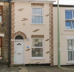 The front exterior of a small two-story house with a white door and two windows in a row of terraced houses at Gulls Nest in Pakefield