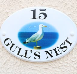 An oval house sign with the number 15 and a seagull image with the text Gulls Nest