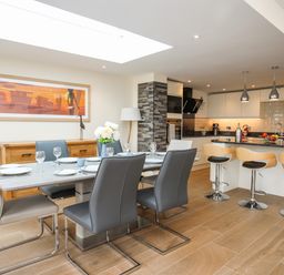 A kitchen and dining area with a dining table set with plates and glasses and bar stools at The Herun in Rhosneigr
