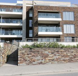 The exterior of a three story building with balconies and stone walls at Newquay Fistral Beach View in Newquay