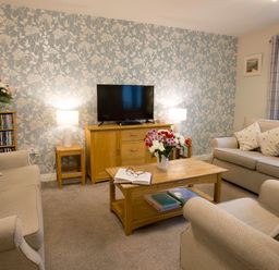 A living room with two sofas armchair wooden coffee table and TV unit at Honeybee Cottage in Berrier near Penruddock