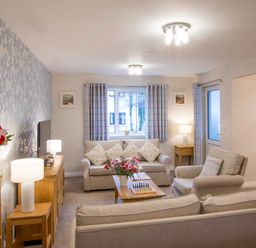 A living room with sofas a coffee table a television and lamps at Honeybee Cottage in Berrier near Penruddock