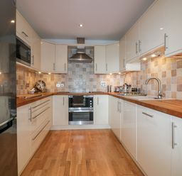 A kitchen with wooden countertops stainless steel appliances and tiled backsplash at The Bolt Hole in Downderry