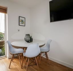 A dining area with a round table and four chairs near a sliding door leading to an outdoor space at The Bolt Hole in Downderry