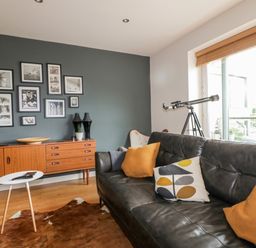 A living room with leather sofas cushions telescope and picture frames on the wall at The Bolt Hole in Downderry