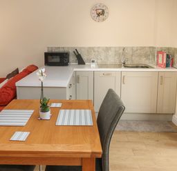 A kitchen and dining area with a wooden table set with placemats and a potted plant at Nuthatch Barn in Hensol near Pontyclun