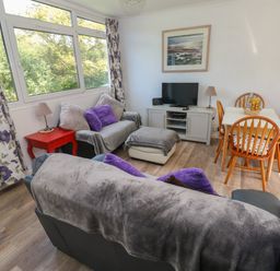 A living room with sofas pillows a television dining table and chairs at Y Twll Bollt The Bolt Hole in Folkeston Hill Nolton Haven West Wales amp Pembrokeshire