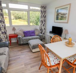 A living room with sofas pillows and a dining table with chairs at Y Twll Bollt (The Bolt Hole) Folkeston Hill Nolton Haven West Wales & Pembrokeshire