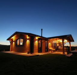 A log cabin with outdoor seating and lighting at dusk at Bacheiddon Log Cabin Aberhosan near Machynlleth