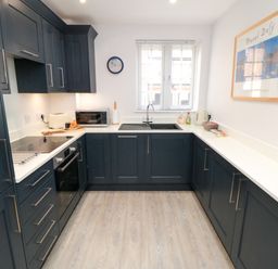 A kitchen with dark cabinets and white countertops a microwave sink and coffee machine at Esk Retreat in Whitby