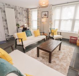 A living room with sofas yellow cushions a coffee table a desk and a TV at Morawel Newport Pembrokeshire