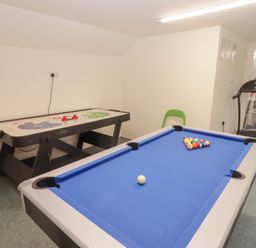 A recreation room with a blue pool table air hockey table and a treadmill at Morawel Newport Pembrokeshire