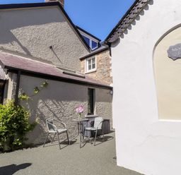 An outdoor seating area with two chairs and a small table with flowers outside a building at Morawel Fach in Newport Pembrokeshire