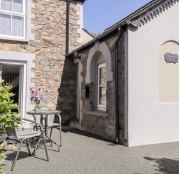 A stone and white exterior wall with a small table and chairs outside with flowers on the table at Morawel Fach in Newport Pembrokeshire