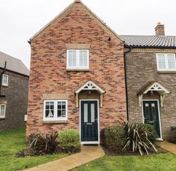 Two attached brick houses with black doors and white framed windows with small gardens and pathways in front
