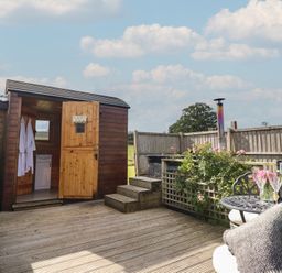 An outdoor area with a wooden cabin and seating at Embden Pod at Banwy Glamping Llanfair Caereinion