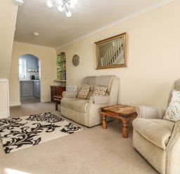 A living room with armchairs a wooden side table a TV on a wooden cabinet and a patterned rug at Molly's Bit in Church Westcote near Bourton-On-The-Water