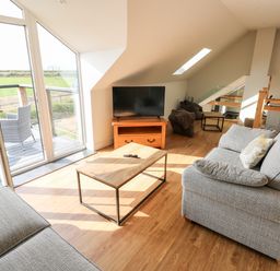 A living room with two sofas a coffee table a television and glass doors leading to a balcony at Glowty Brynbedw in Efailwen