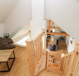 A wooden staircase leading down to a kitchen area with a dining table set with plates and chairs at Glowty Brynbedw in Efailwen