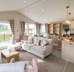 An open living and kitchen area with sofas dining table and kitchen island at Sea Holly Lodge in Runswick Bay