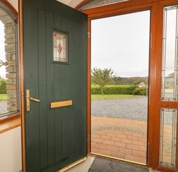 An open front door with stained glass panels beside a window showing a garden driveway and lawn at Redford View in Culdaff County Donegal
